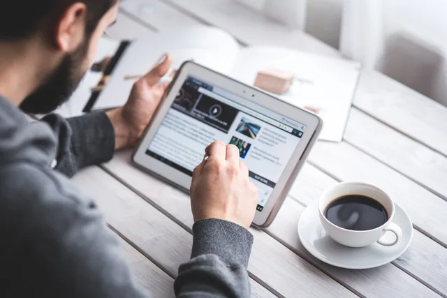 A man uses a tablet to browse news while enjoying a cup of coffee, stylus in hand. Two newsletter suppliers against a manual baseline on one paid-access case